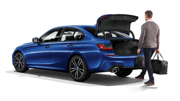 BMW 3-serie Sedan, automatisk åbning af bagagerum. Parkeret BMW 3-serie Sedan med fører, der aktiverer den automatiske åbning af bagagerummet med foden.