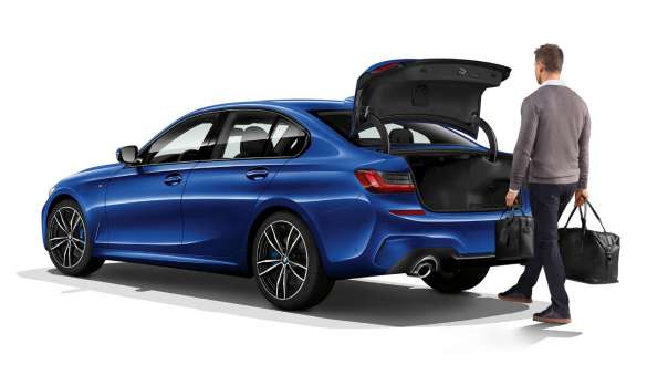 BMW 3-serie Sedan (G20), automatisk bagklapfunktion. Parkeret BMW 3-serie Sedan (G20) set bagfra let drejet med fører, der aktiverer den berøringsfri åbning af bagagerummet med foden.