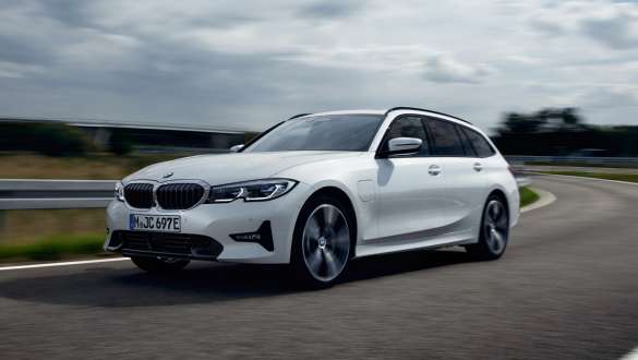 Plug-in-hybrid BMW 3er Touring 2021 G21 set forfra let drejet kørende Plug-in-hybrid BMW 3-serie Touring 2021 G21 forfra let drejet kørende på en vej
