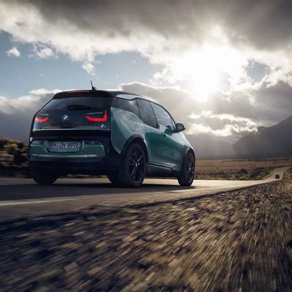 BMW i3 2018 set bagfra let drejet kørende på en landevej BMW i3 I01 2018 Jucaro Beige med detaljer i Frozen Grey metallic set bagfra let drejet kørende på en landevej