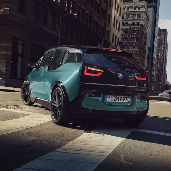BMW i3 2018 set bagfra let drejet kørende BMW i3 I01 2018 Jucaro Beige med detaljer i Frozen Grey metallic set bagfra let drejet kørende i urbane omgivelser