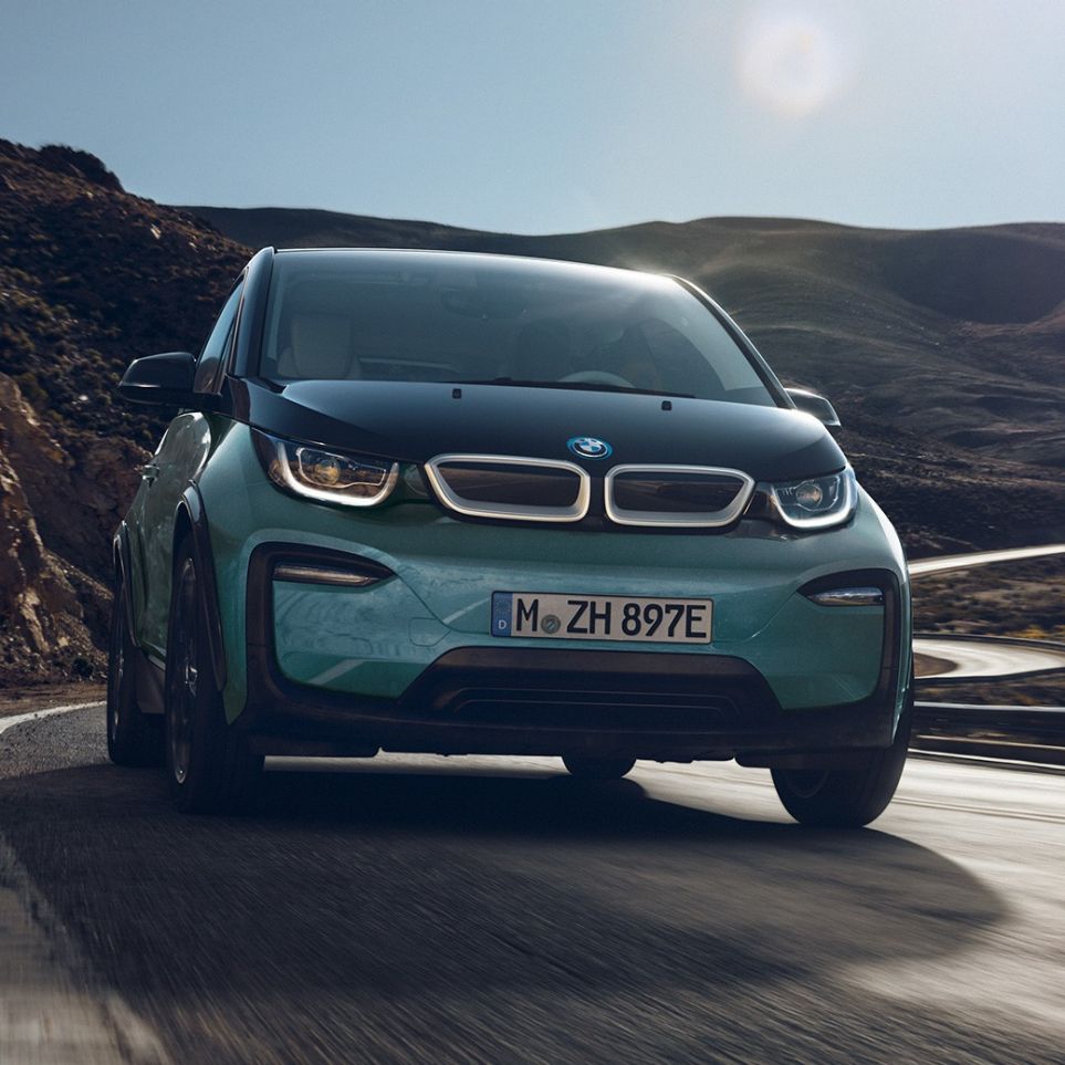 BMW i3 2018 set fra siden kørende BMW i3 I01 2018 Jucaro Beige med detaljer i Frozen Grey metallic set fra siden kørende i urbane omgivelser