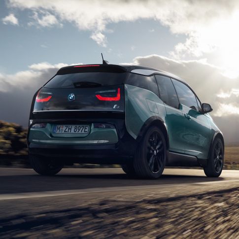 BMW i3 2018 Juraco Beige set bagfra let drejet kørende på en landevej BMW i3 I01 2018 Jucaro Beige med detaljer i Frozen Grey metallic set bagfra let drejet kørende på en landevej