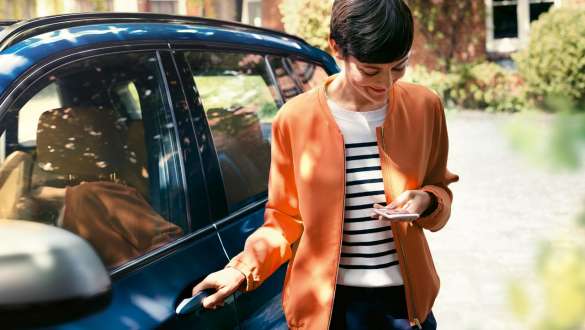 BMW Teleservices BMW Teleservices kvinde med smartphone ved døren til en BMW