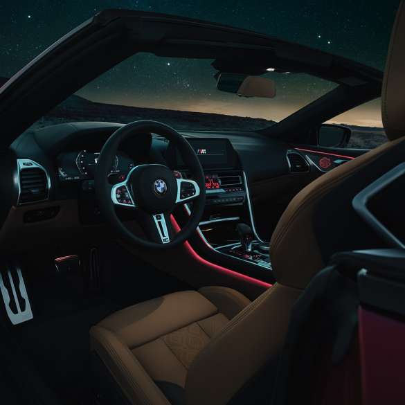 BMW M8 Competition Cabriolet, cockpit. BMW M8 Competition Cabriolet, cockpit om natten med M læderrat og rødt Ambient Light-kabinelys.