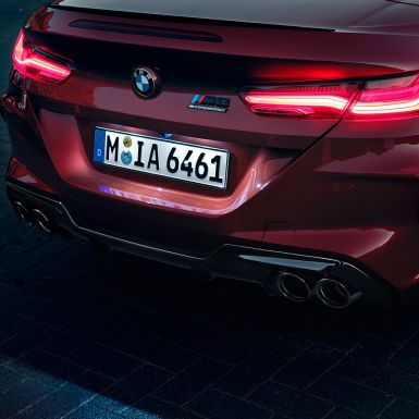 BMW M8 Competition Cabriolet set bagfra tæt på. BMW M8 Competition Cabriolet i Motegi Red metallic set bagfra tæt på med LED-baglygter og M8 Competiton badge.