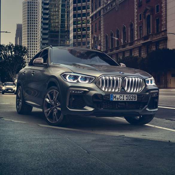 BMW X6 adaptiv M undervogn Professional. BMW X6 set forfra let drejet foran et urbant miljø.