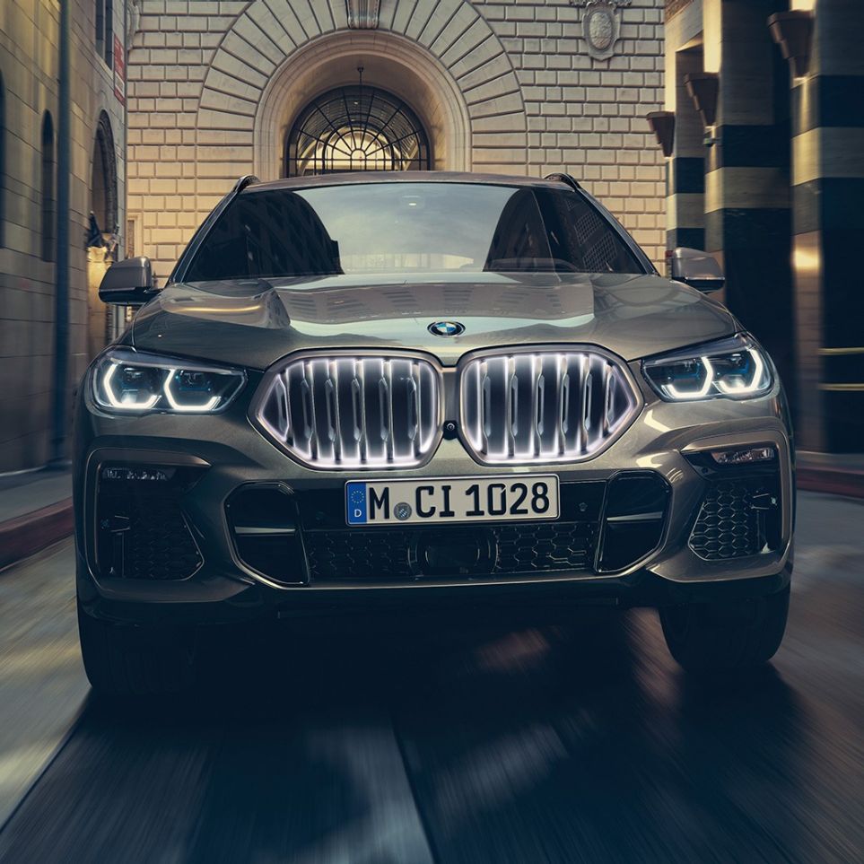 BMW X6 med BMW nyre ‘Iconic Glow’. BMW X6 set forfra foran et urbant miljø.