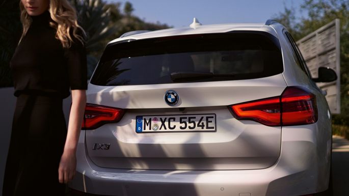 Bagende med BMW i specifik diffusor BMW iX3 G08 set bagfra med en kvinde Bagende med BMW i specifik diffusor BMW iX3 G08 2020 Mineral White metallic set bagfra med en kvinde