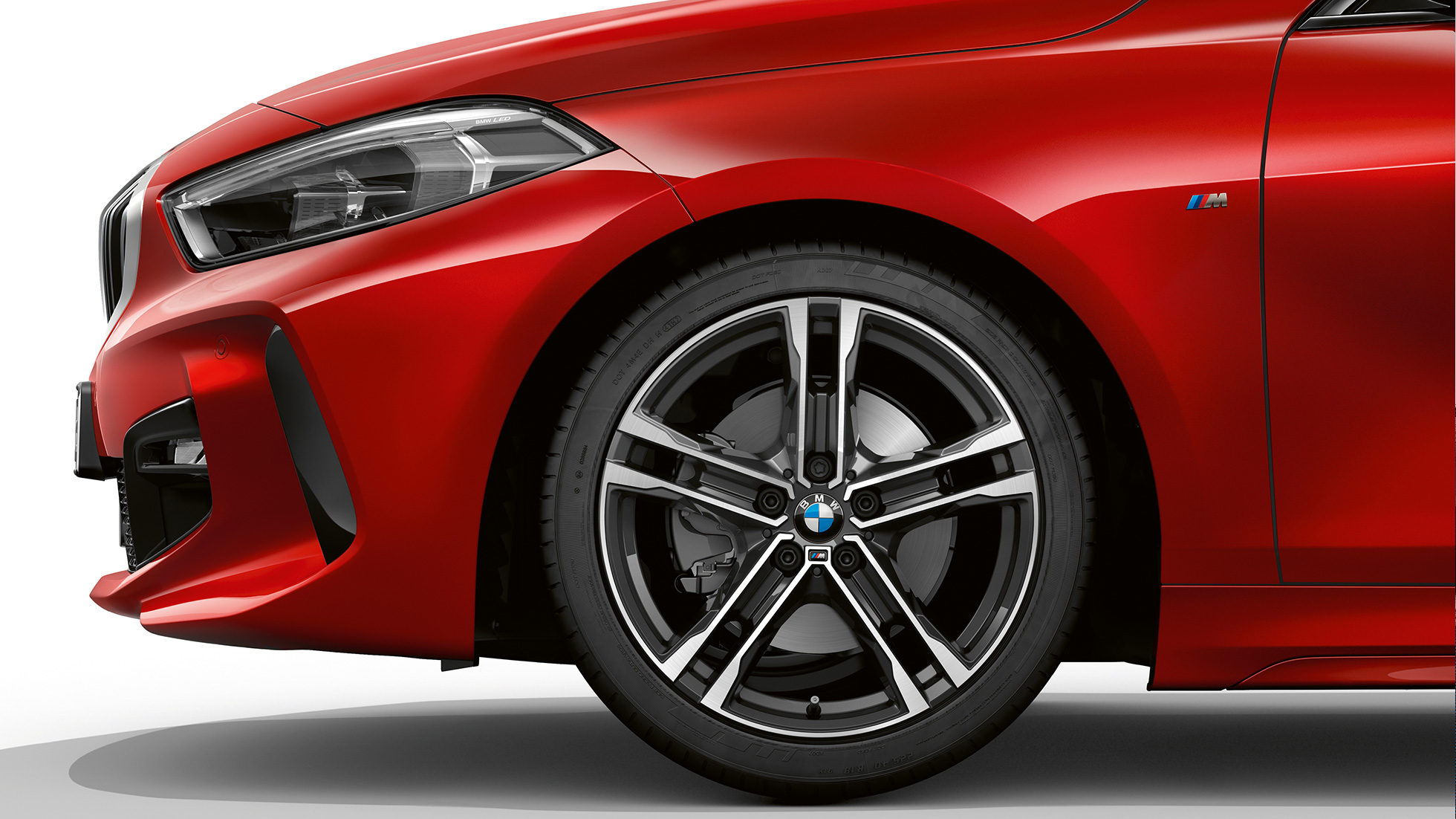 BMW 1-serie model M Sport, skråt forfra. BMW 1-serie model M Sport i Melbourne Red metallic set skråt forfra med 17" M letmetalfælge med dobbelteger 550 M Bicolor.