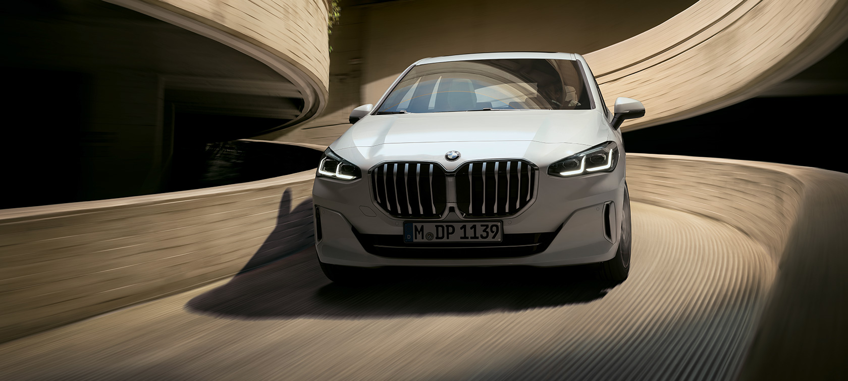 BMW 2-serie Active Tourer U06 2021 Mineral White metallic set forfra k&oslash;rende i et parkeringshus