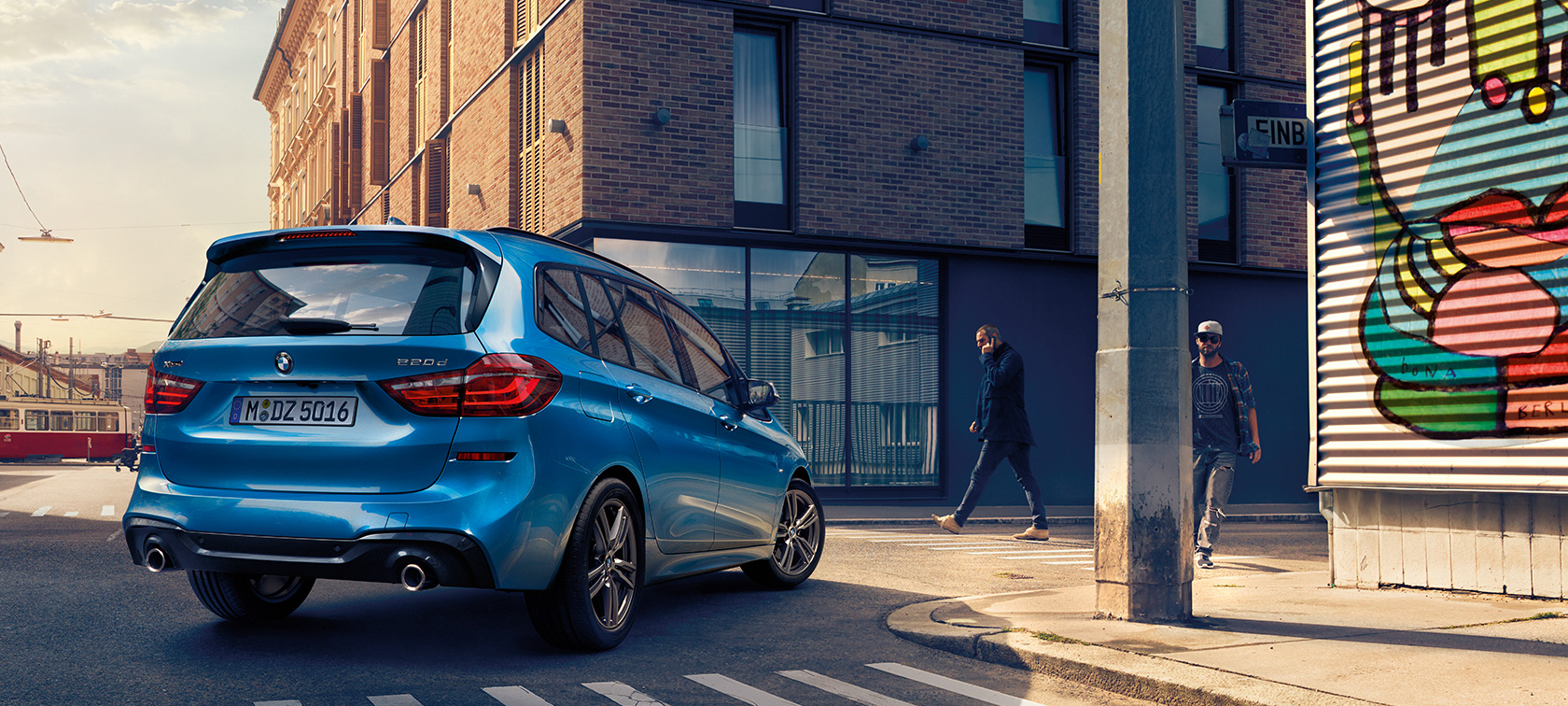 BMW 2-serie Gran Tourer i fugleperspektiv Mand ved siden af BMW 2-serie Gran Tourer F46 Facelift 2018 Estoril Blue metallic set i fugleperspektiv parkerende på en vej