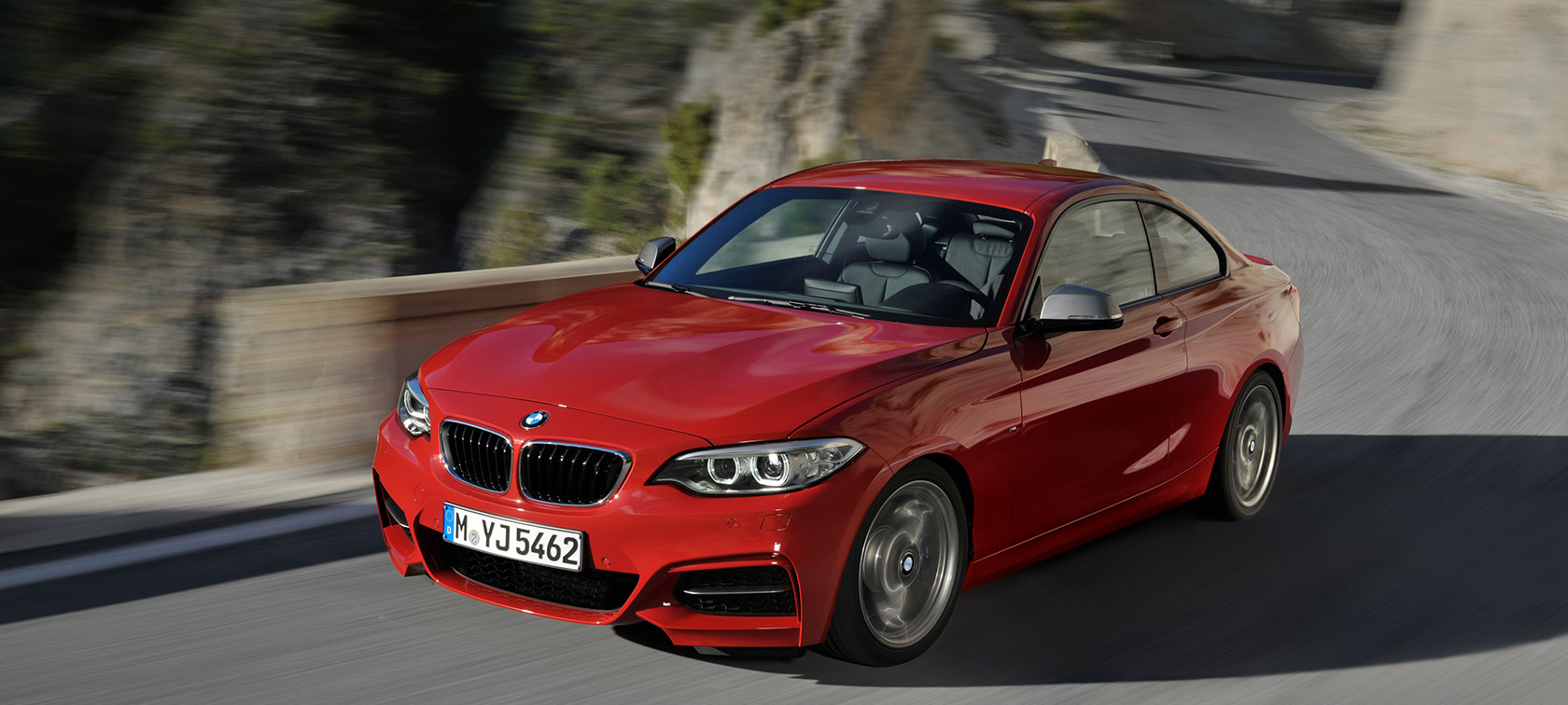 BMW 2-serie set forfra let drejet kørende på vej foran landskab BMW 2-serie modeller BMW set forfra let drejet kørende på vej foran landskab