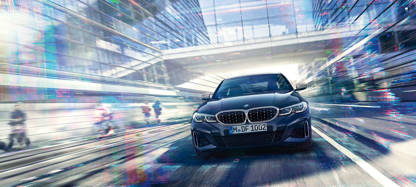 BMW 3-serie Sedan, BMW M340i xDrive set forfra. Kørende BMW M340i xDrive Sedan set forfra mellem glasbygninger i urbant miljø.