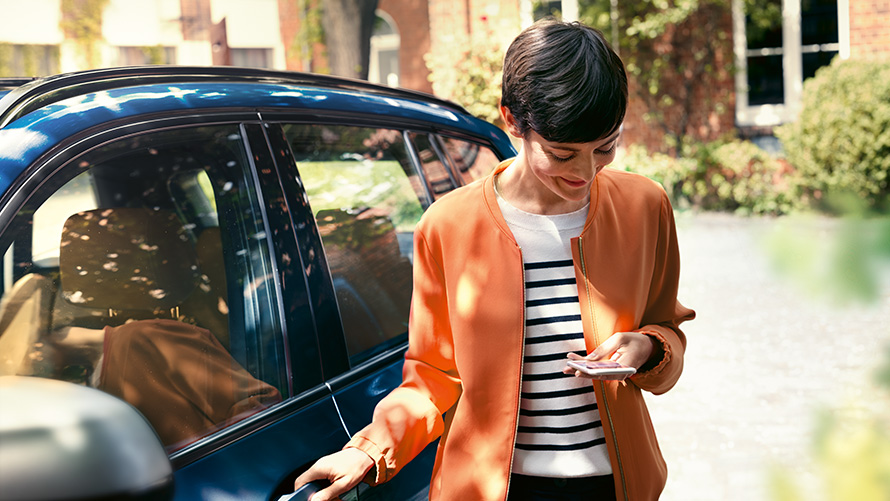 BMW Service en kvinde med en smartphone ved døren til sin BMW BMW Service en kvinde med en smartphone ved døren til sin BMW