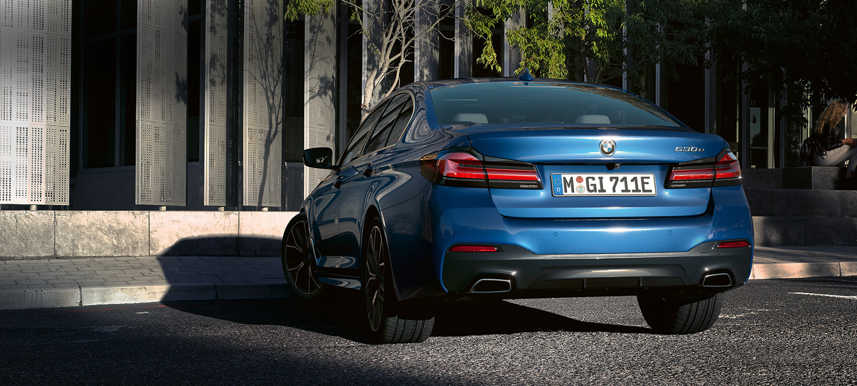 BMW 5-serie Sedan eDrive (G30), Phytonic Blue metallic, set bagfra parkerende foran en bygning