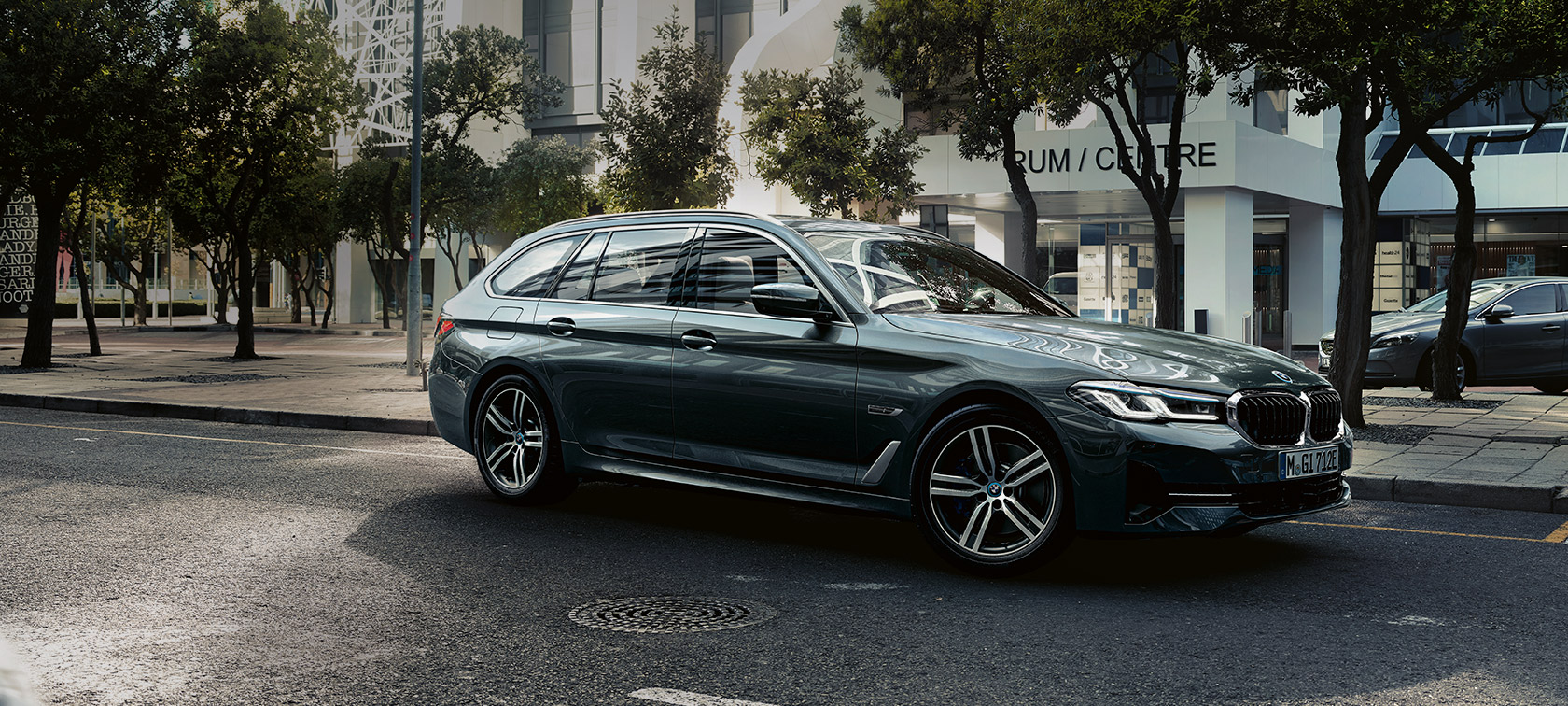 BMW 5-serie Touring G31 Facelift 2020 Sophisto Grey 7/8 frontvisning kørende i udkanten af en by