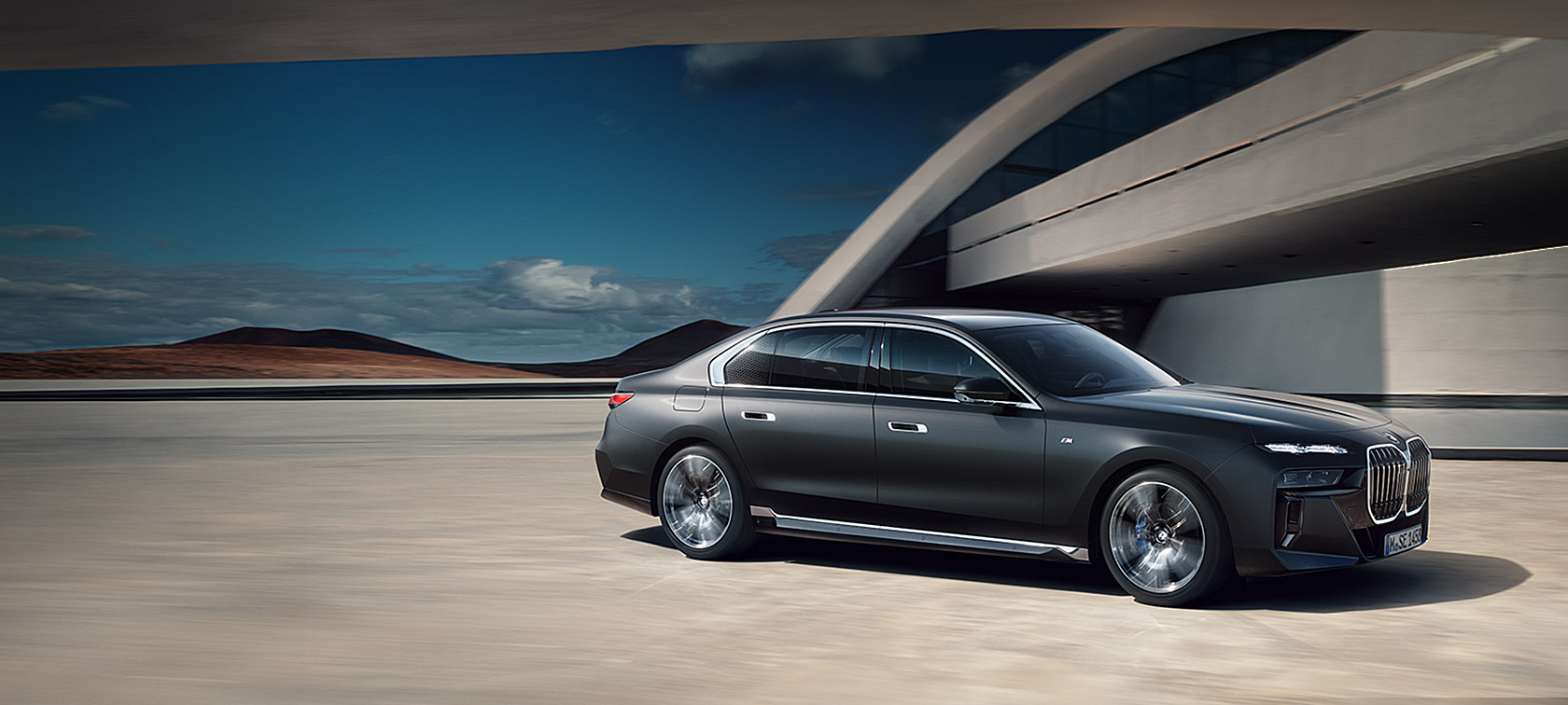 BMW 7-serie Sedan G70 ICE M sportspakke Frozen Deep grey metallic ¾ frontvisning stående foran bygning