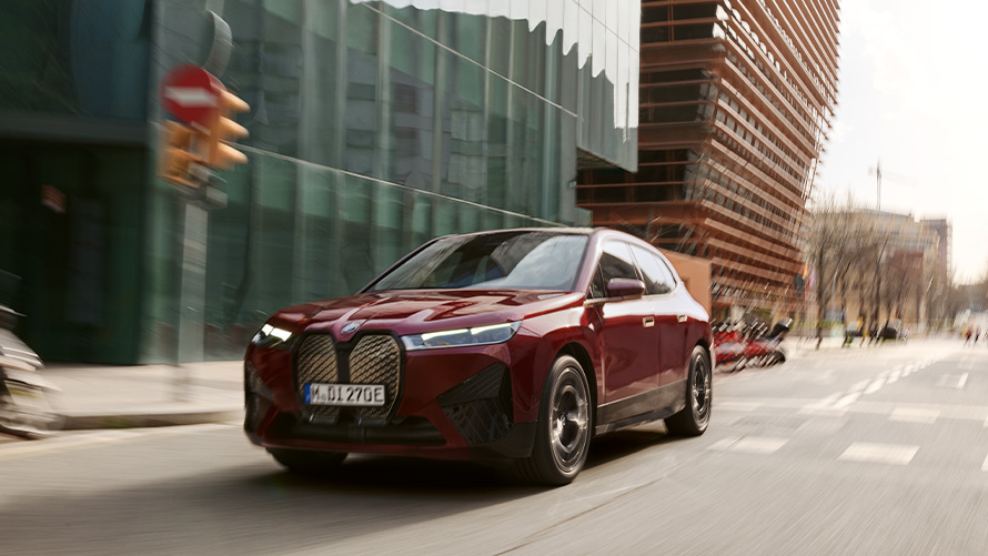 BMW iX i20 elektrisk SUV BMW iX xDrive50 førerassistance BMW iX i20 2021 elektrisk SUV BMW iX xDrive50 Aventurin Red kørende i urbane omgivelser