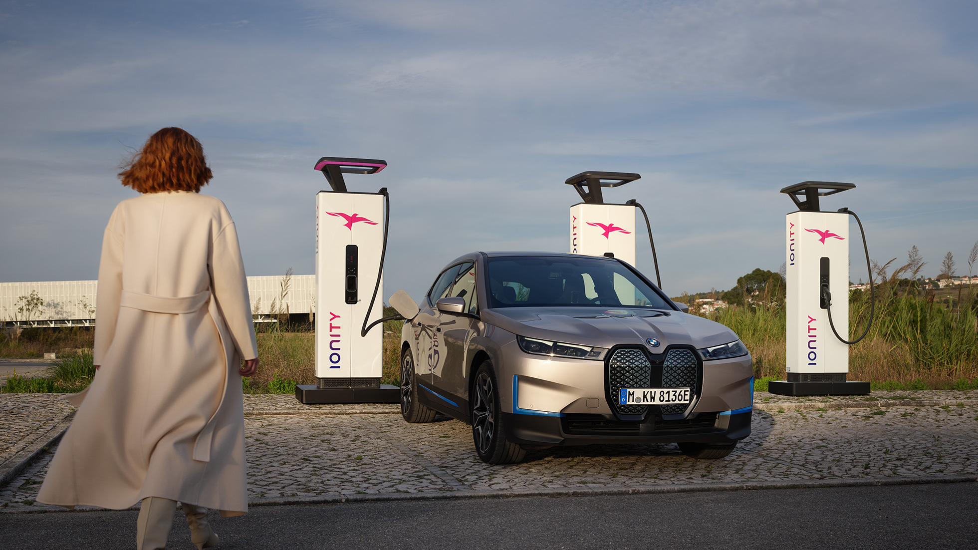 BMW iX set forfra let drejet ved en ladestation BMW iX Cashmere Silver i20 set forfra let drejet ved en ladestation