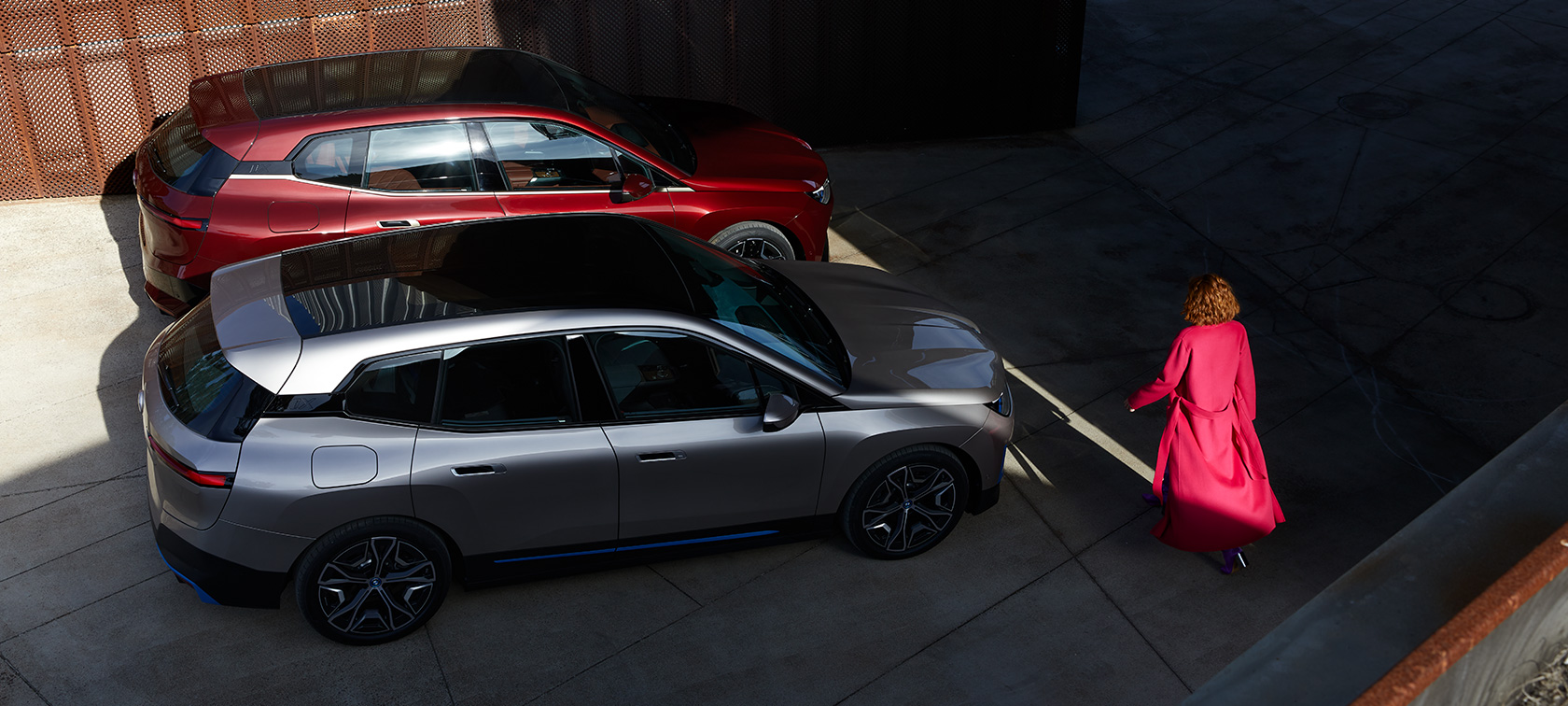 BMW iX set i fugleperspektiv med model BMW iX Aventurin Red og Cashmere Silver i20 set i fugleperspektiv med model