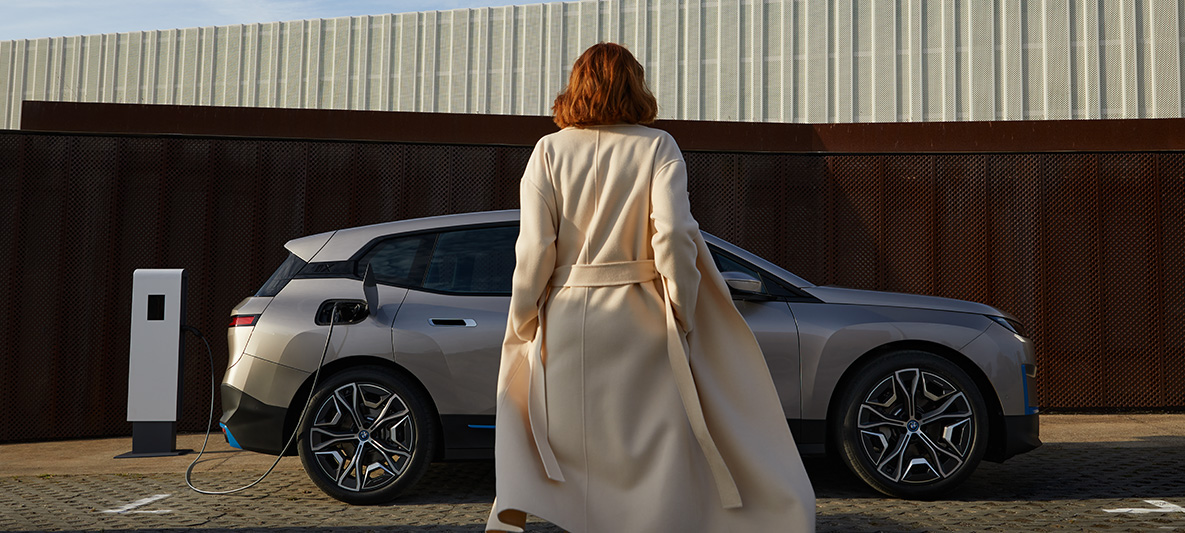 BMW iX set fra siden parkeret BMW iX Cashmere Silver i20 set fra siden parkeret med model foran