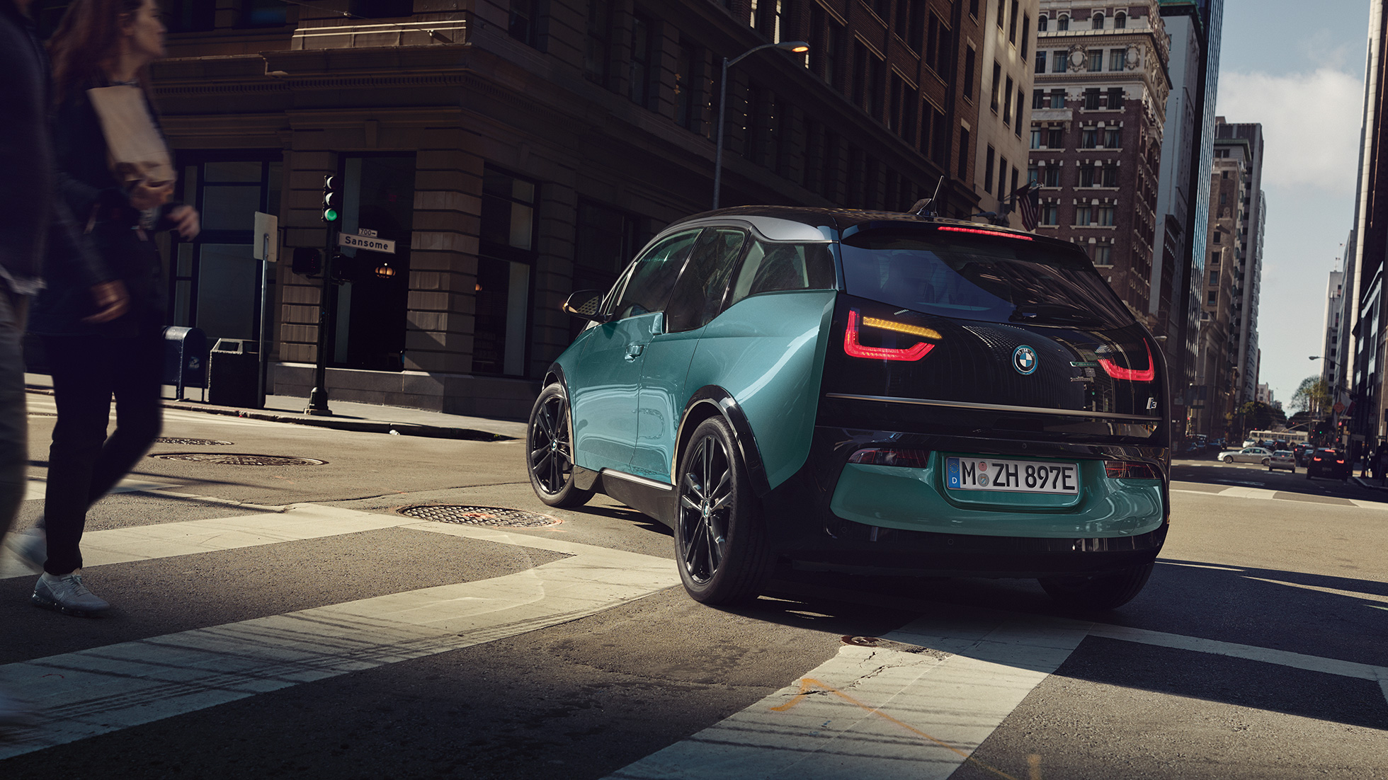 BMW i3 2018 set bagfra let drejet kørende BMW i3 I01 2018 Jucaro Beige med detaljer i Frozen Grey metallic set bagfra let drejet kørende i urbane omgivelser