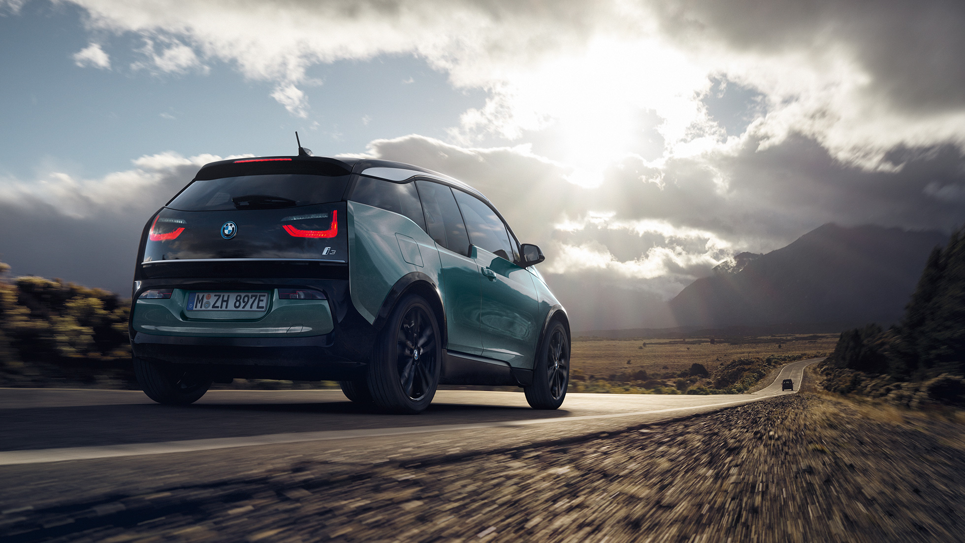 BMW i3 2018 set bagfra let drejet kørende på en landevej BMW i3 I01 2018 Jucaro Beige med detaljer i Frozen Grey metallic set bagfra let drejet kørende på en landevej