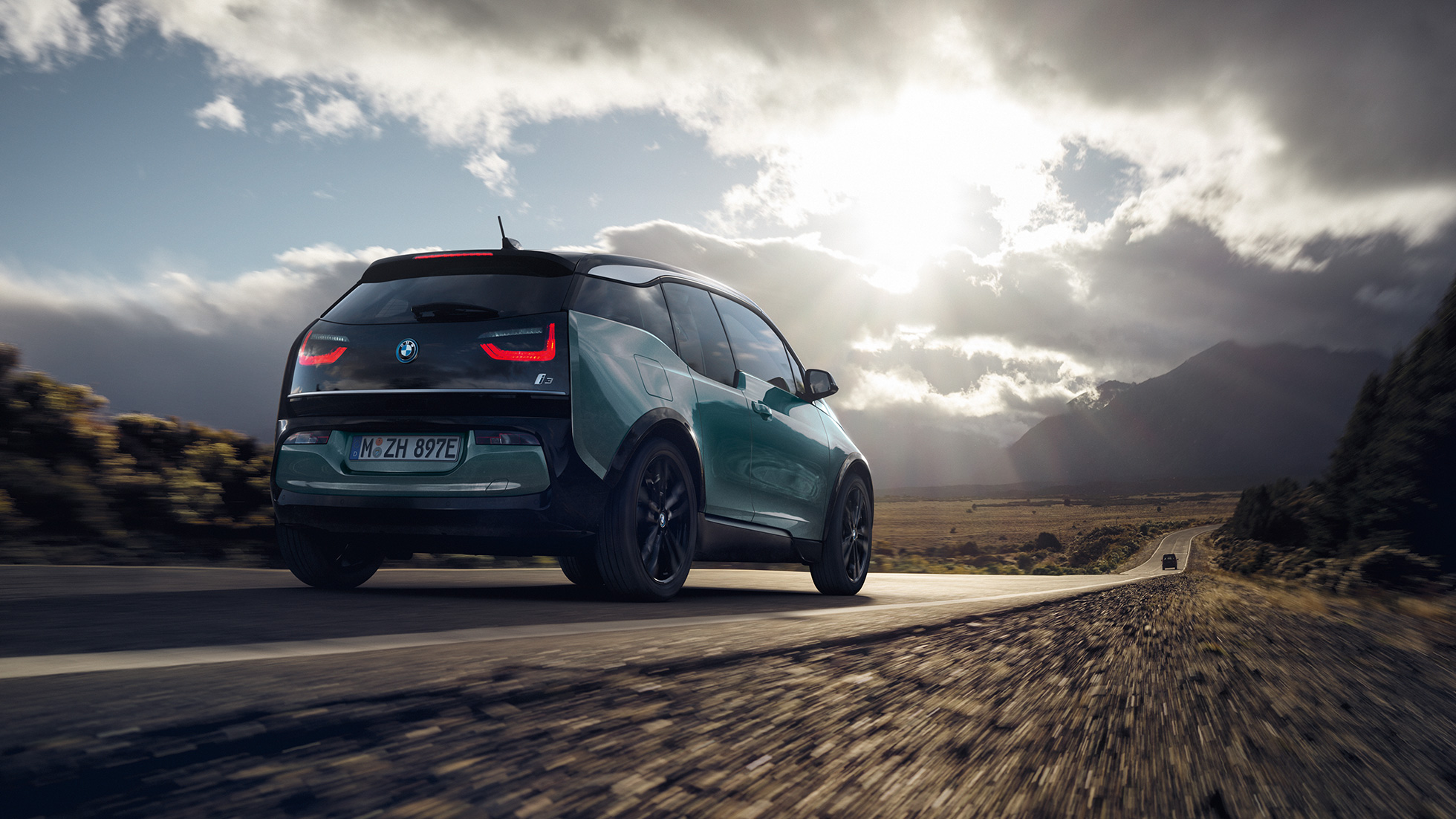 BMW i3 2018 Juraco Beige set bagfra let drejet kørende på en landevej BMW i3 I01 2018 Jucaro Beige med detaljer i Frozen Grey metallic set bagfra let drejet kørende på en landevej