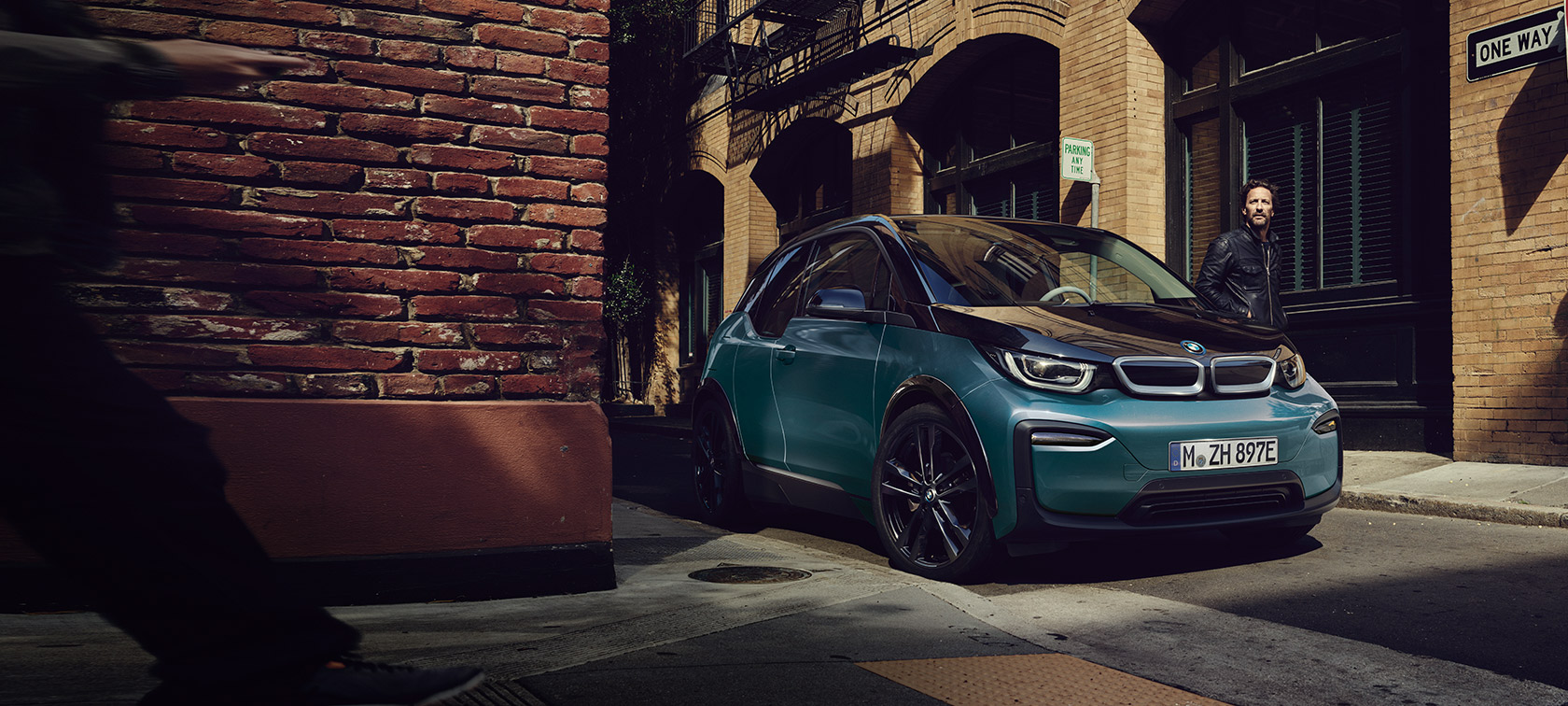 BMW i3 I01 2018 Blue Ridge Mountain med detaljer i Frozen Grey metallic set forfra let drejet parkeret i urbane omgivelser