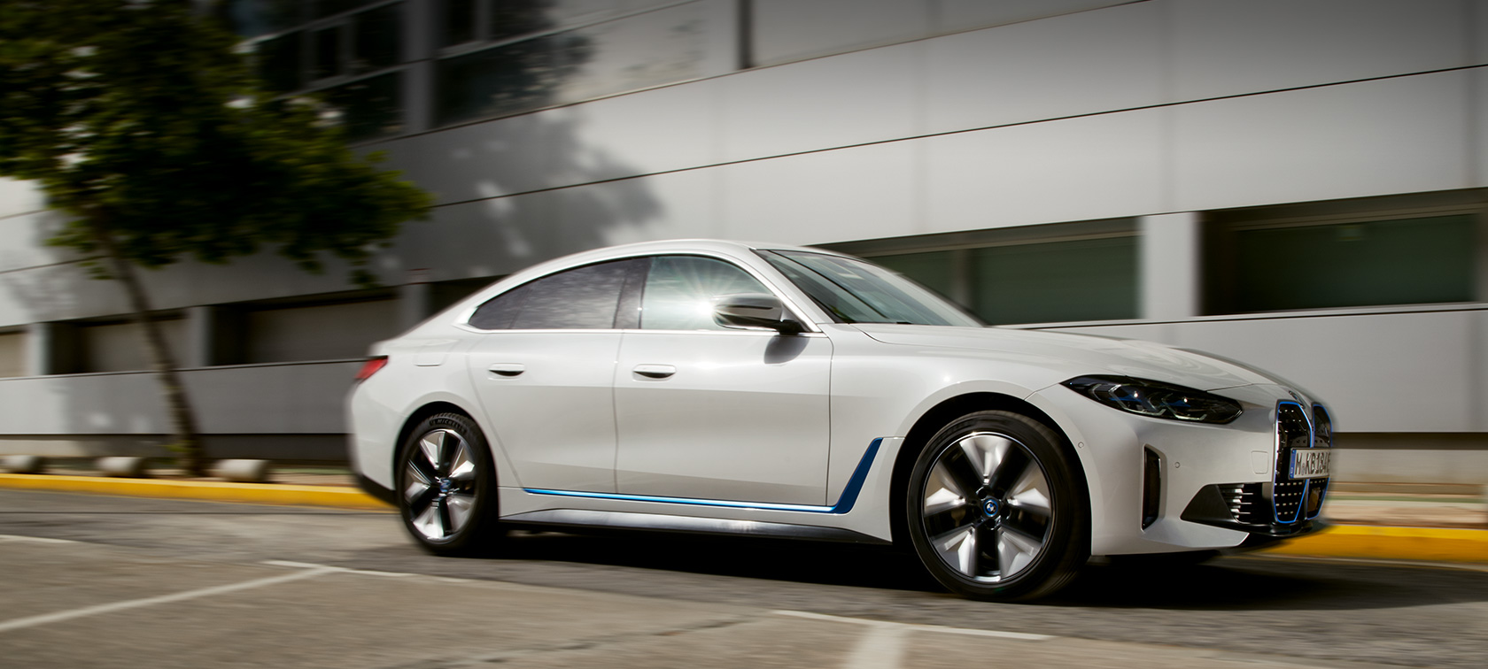 BMW i4 eDrive40 G26 2021 set fra siden let drejet kørende foran en bygning BMW i4 eDrive40 G26 2021 set fra siden let drejet kørende foran en bygning