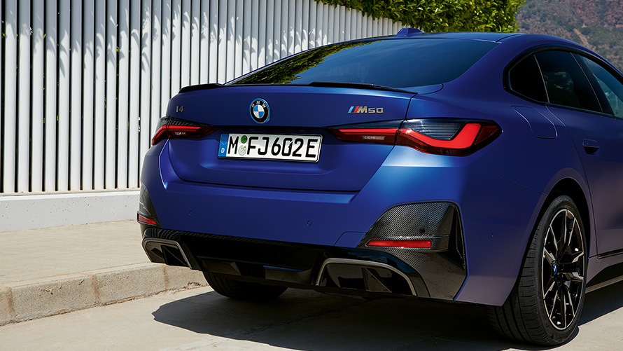 BMW i4 M50 G26 2021 BMW Individual Frozen Portimao Blue metallic set bagfra let drejet stående ved et hvidt hegn