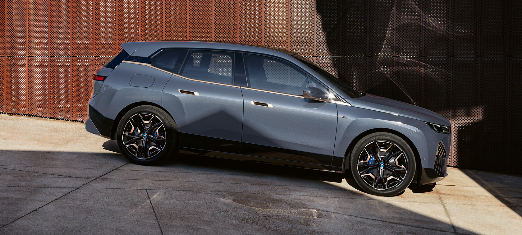 BMW iX M60 i20 2022 elektrisk SUV elbil Oxid Grey metallic set fra siden under parkering
