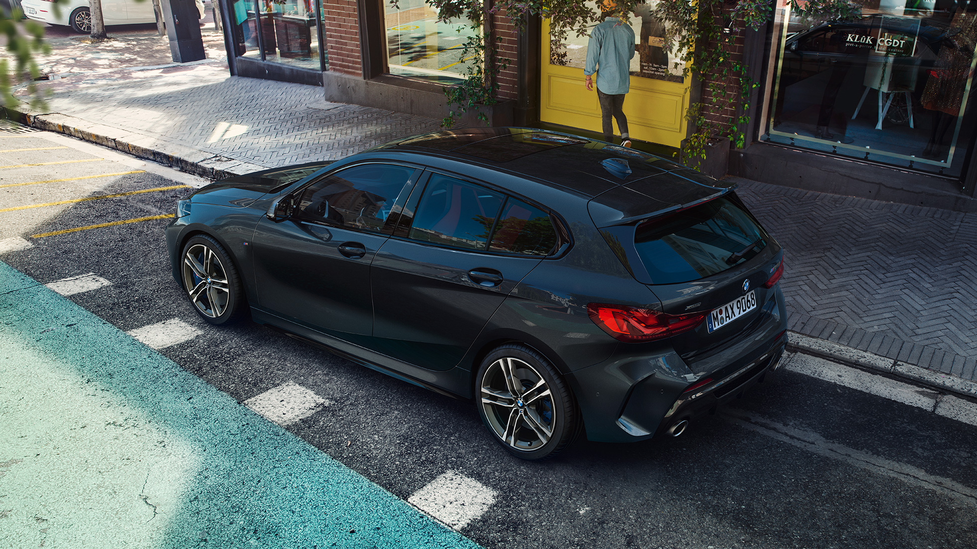 BMW M135i xDrive, parkerende. BMW M135i xDrive i Sapphire Black metallic parkerende, set fra siden i fugleperspektiv.