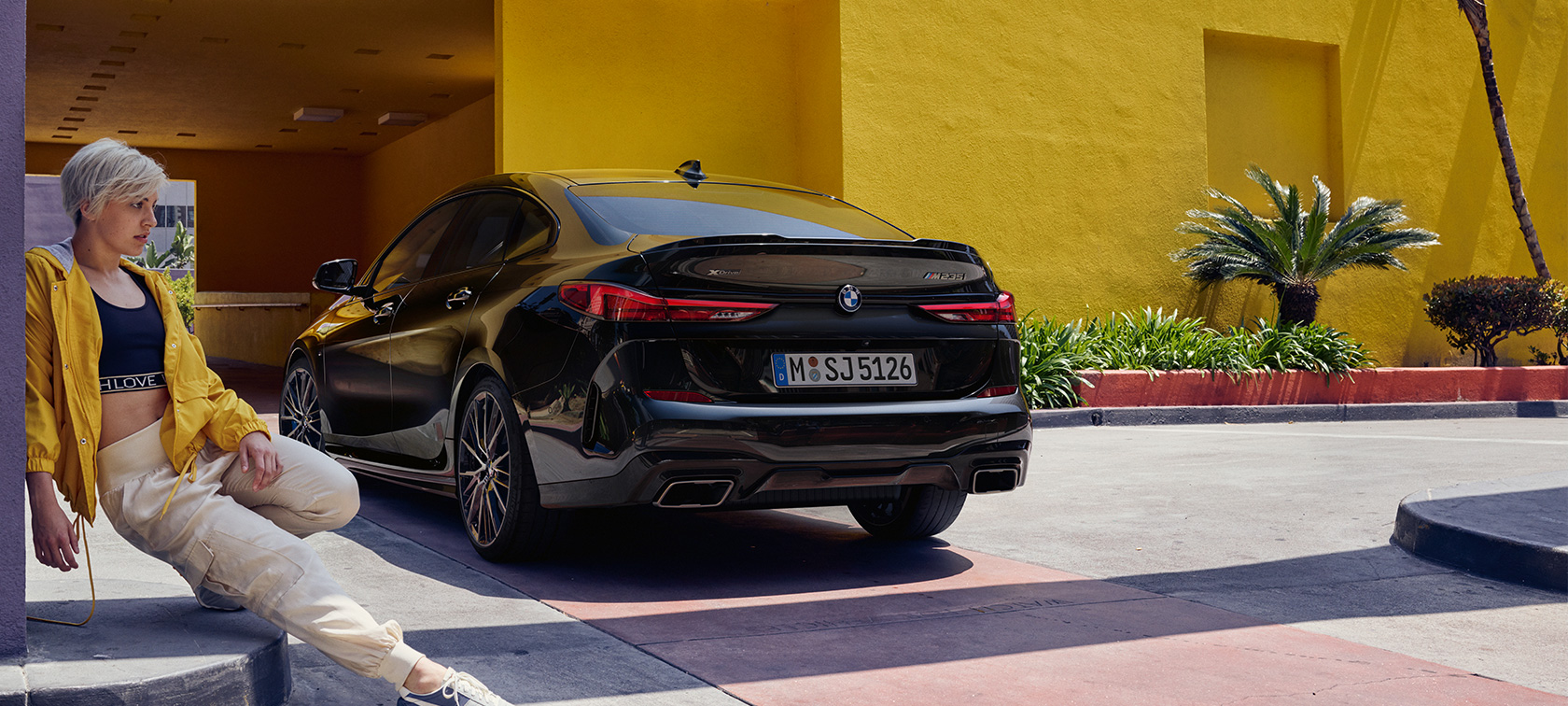 BMW M235i xDrive Gran Coupé set bagfra let drejet BMW M235i xDrive Gran Coupé Black Sapphire metallic F44 set bagfra let drejet med kvinde i forgrunden