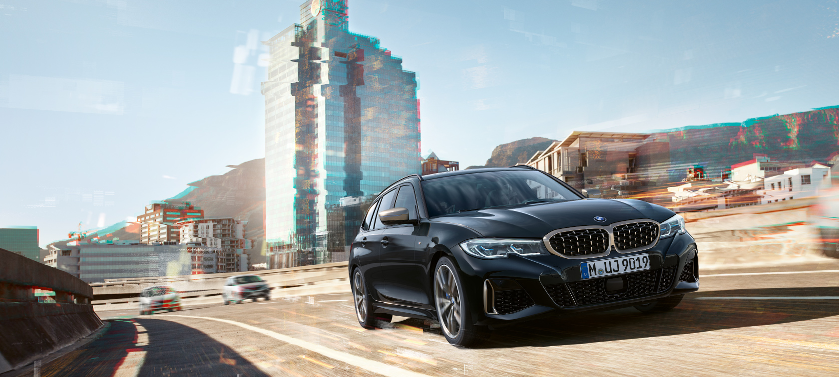 Set forfra let drejet kørende i urbant miljø BMW M340i xDrive Touring set forfra let drejet kørende i urbant miljø