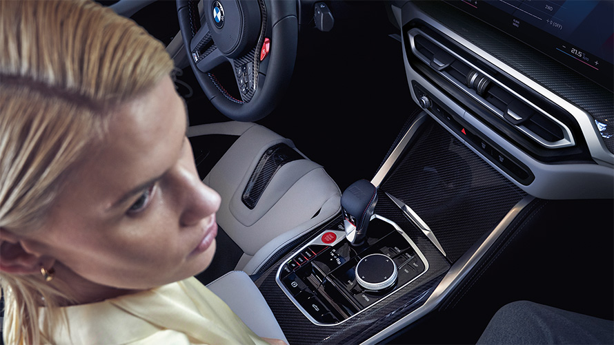 BMW M4 Competition Cabriolet med M xDrive G83 indvendigt udstyr 2021 midterkonsol BMW M4 Competition Cabriolet med M xDrive G83 2021 midterkonsol og kvinde på passagersæde
