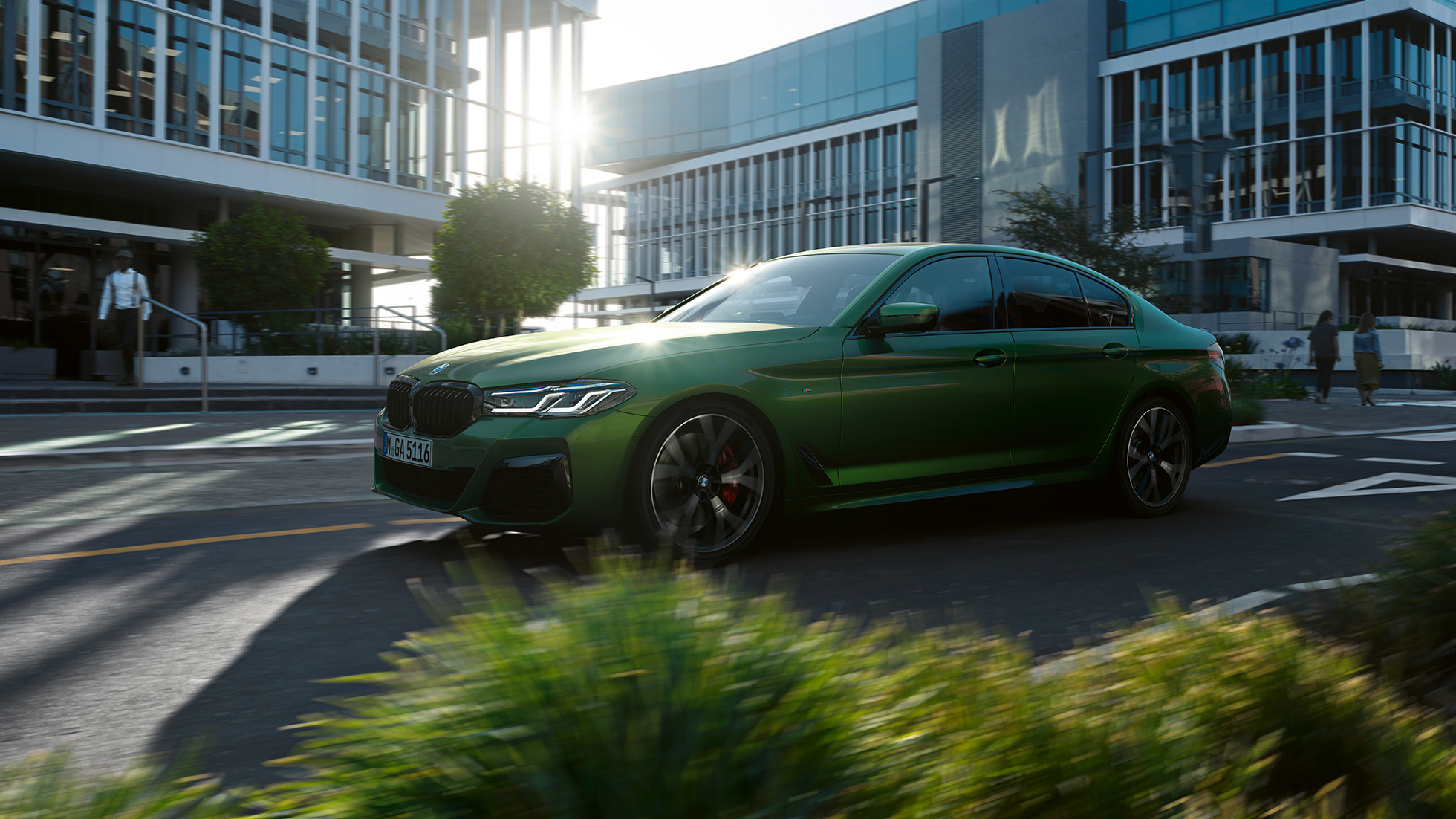BMW M550i xDrive Sedan G30 LCI Facelift 2020 set fra siden kørende BMW M550i xDrive Sedan G30 LCI Facelift 2020 BMW Individual Verde Ermes metallic set fra siden kørende i en by
