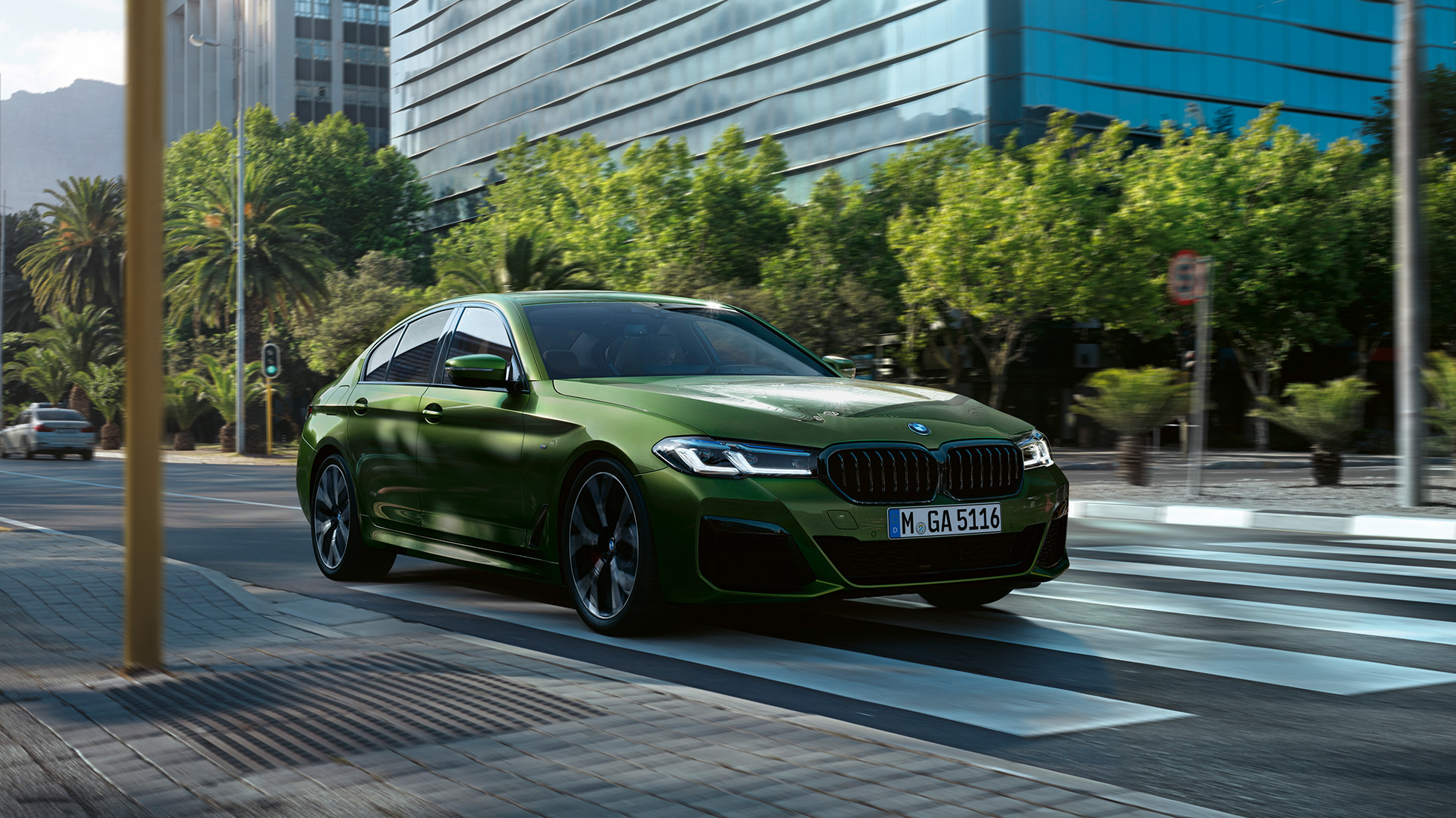 BMW M550i xDrive Sedan G30 LCI Facelift 2020 set forfra let drejet kørende BMW M550i xDrive Sedan G30 LCI Facelift 2020 BMW Individual Verde Ermes metallic set forfra let drejet kørende i en by