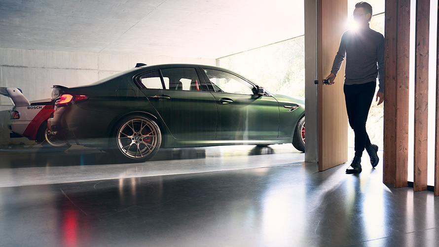 BMW M5 CS F90 2021 Frozen Deep Green metallic set fra siden i en garage