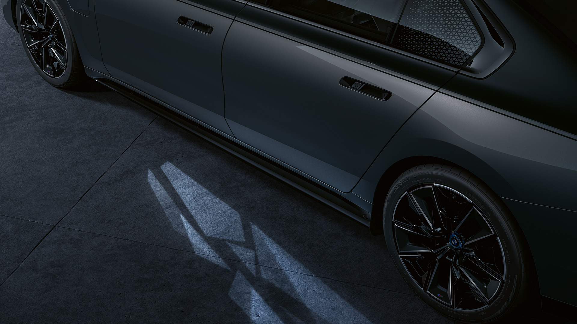 Lyskoncept BMW M760e xDrive Sedan G70 Lyskoncept BMW M760e xDrive Sedan G70 two tone-lakering Sapphire Black metallic BMW Individual Dravit Grey metallic nærbillede fra siden med tændt Welcome Light Carpet