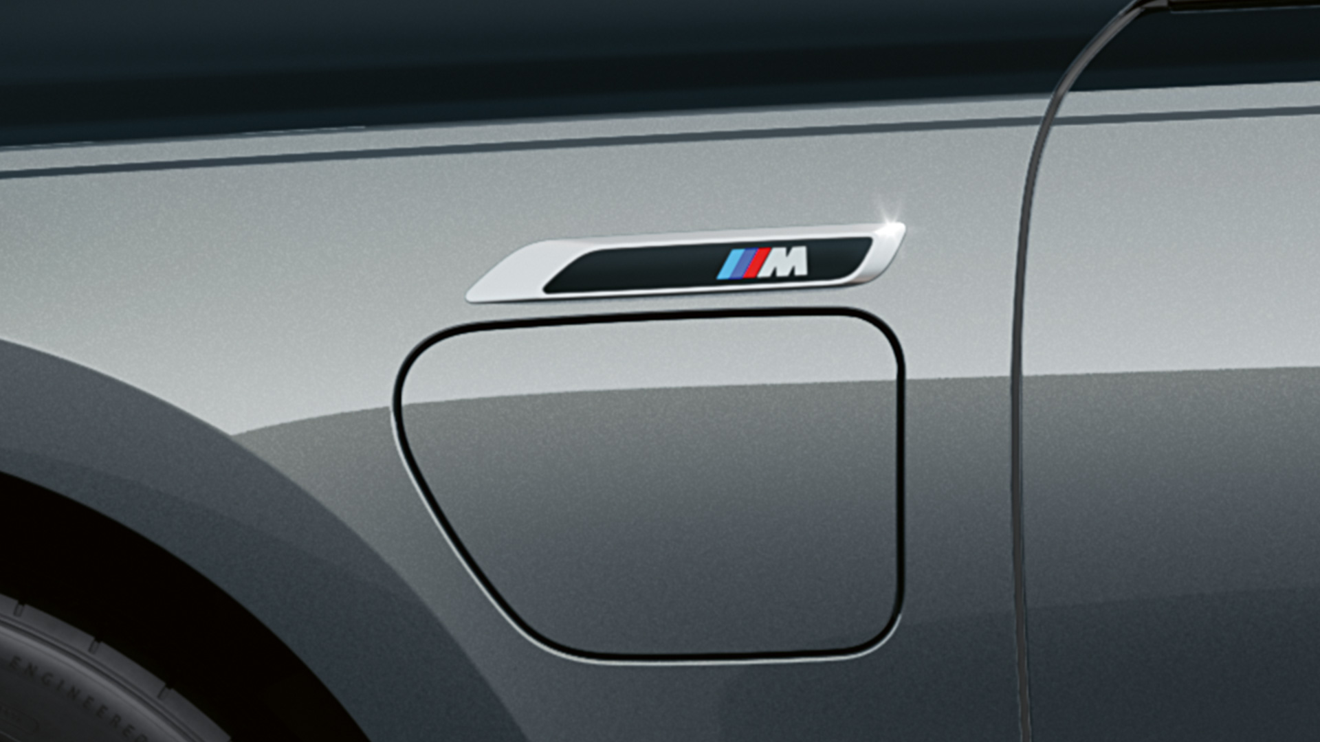 M badge BMW M760e xDrive Sedan G70 M badge BMW M760e xDrive Sedan G70 M Performance pakke BMW Individual two tone-lakering Sapphire Black metallic BMW Individual Dravit Grey metallic nærbillede set fra siden