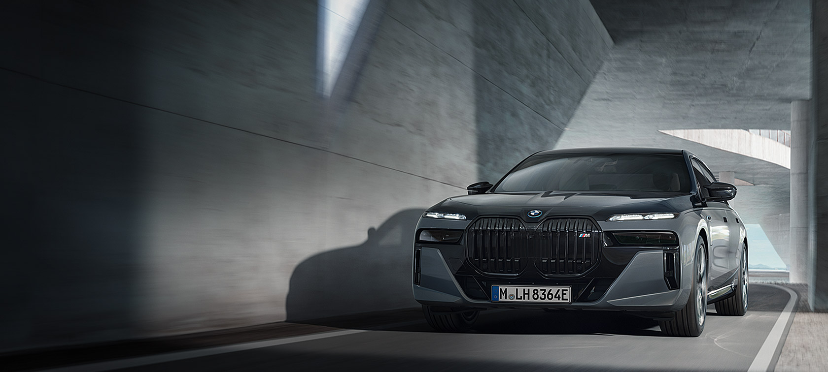 BMW M760e xDrive Sedan G70 M Performance pakke BMW Individual two tone-lakering Sapphire Black metallic BMW Individual Dravit Grey metallic set forfra let drejet kørende på en vej