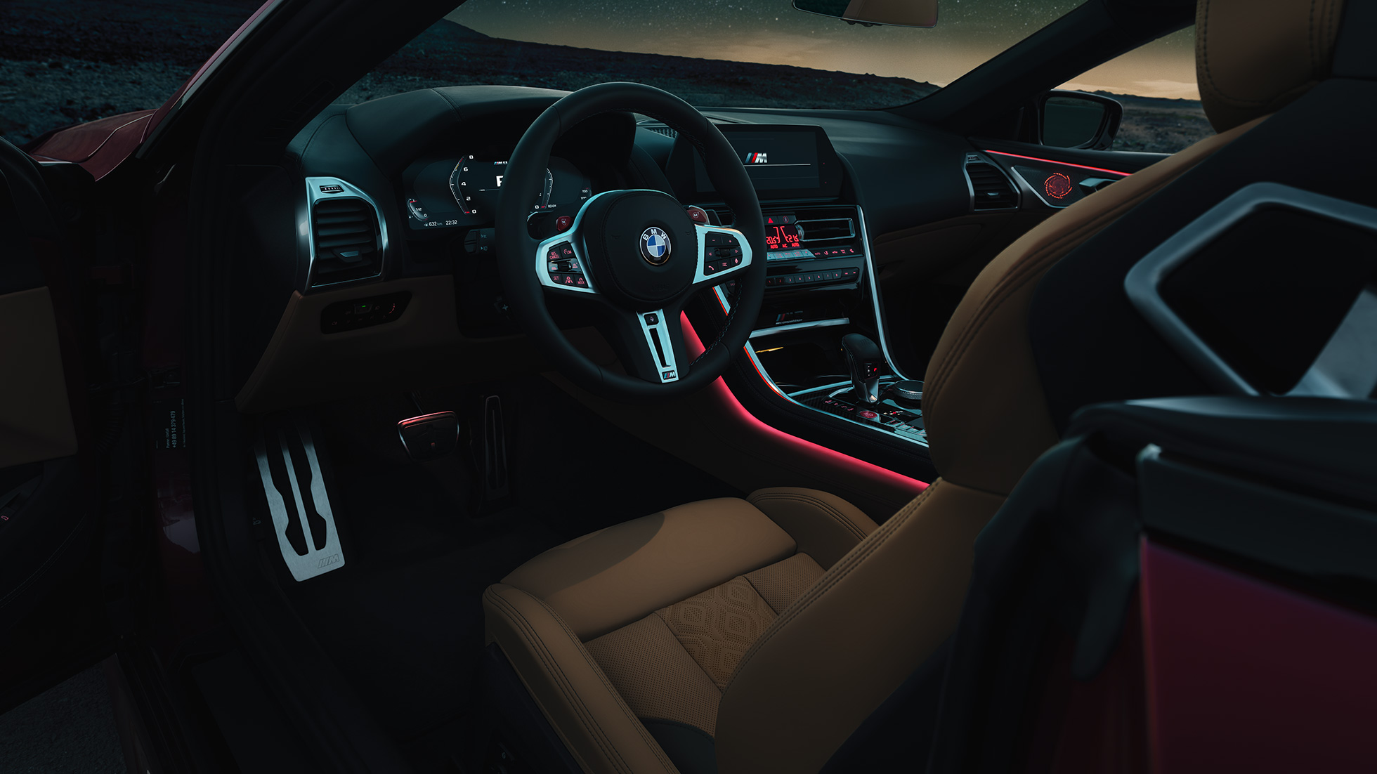 BMW M8 Competition Cabriolet, cockpit. BMW M8 Competition Cabriolet, cockpit om natten med M læderrat og rødt Ambient Light-kabinelys.