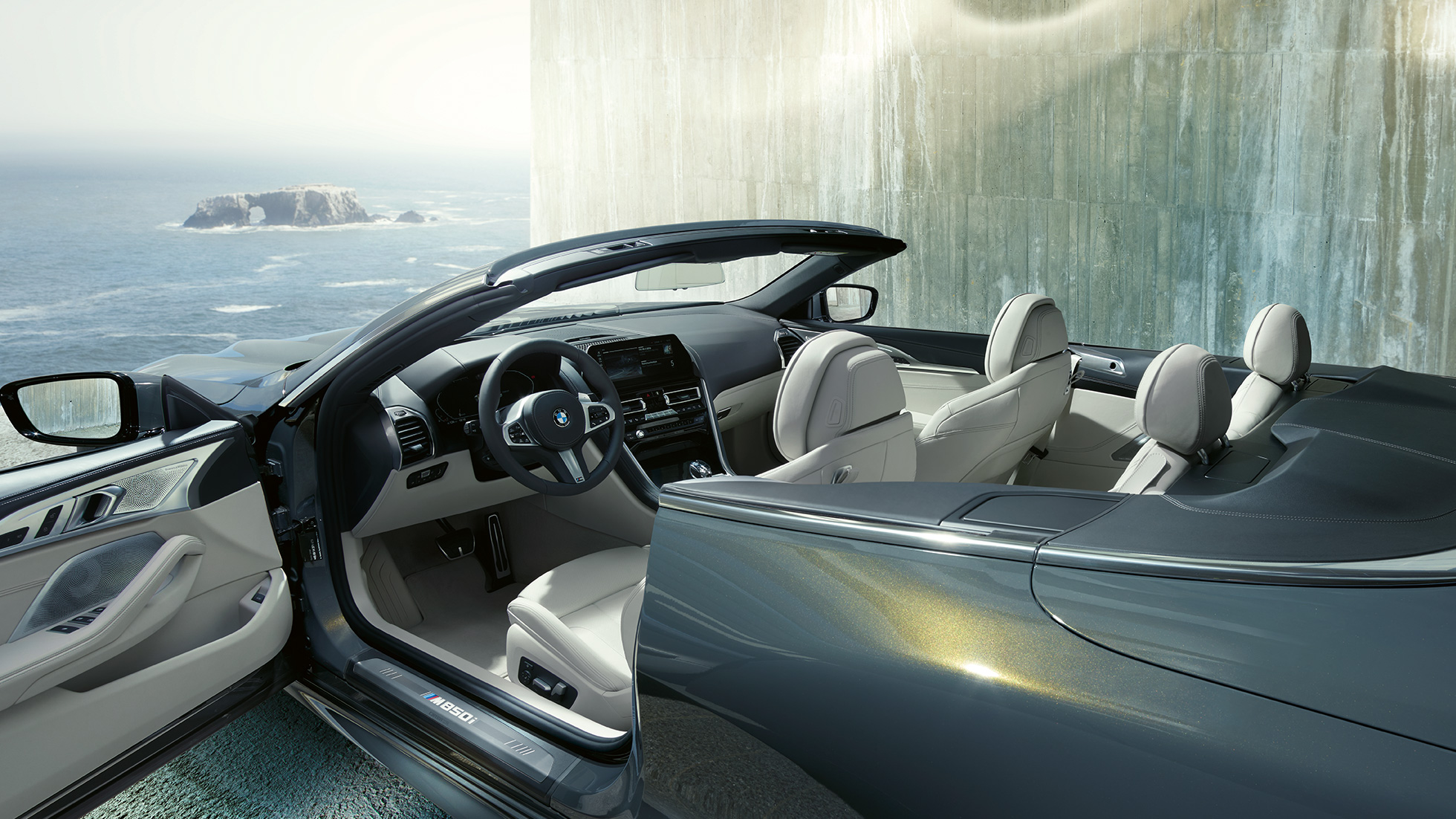 BMW M850i xDrive Cabriolet, interiør. BMW M850i xDrive Cabriolet i Dravit Grey metallic med åben kaleche, interiør med M læderrat og BMW Individual læderpakke 'Merino' i Ivory White.