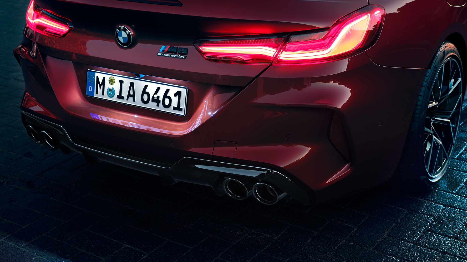 BMW M8 Competition Cabriolet set bagfra tæt på. BMW M8 Competition Cabriolet i Motegi Red metallic set bagfra tæt på med LED-baglygter og M8 Competiton badge.