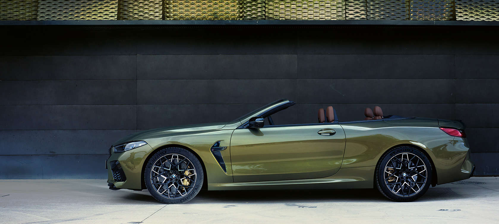 BMW M8 Competition Cabriolet F91 LCI Facelift 2022 set fra siden stående BMW M8 Competition Cabriolet F91 LCI Facelift 2022 BMW Individual Brass metallic set fra siden stående med åben dør og kvindelig model