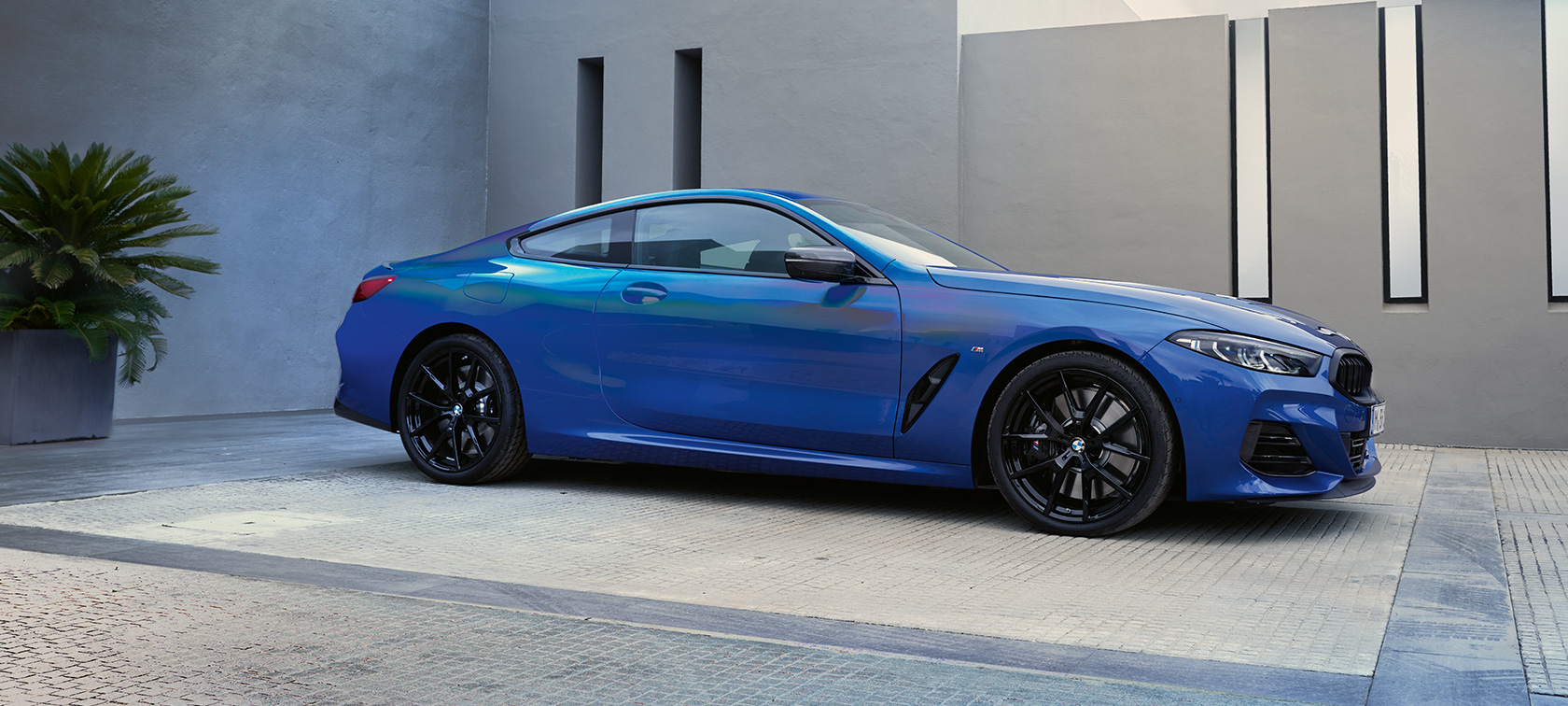 BMW M850i xDrive Coupé G15 LCI Facelift 2022 set fra siden BMW M850i xDrive Coupé G15 LCI Facelift 2022 M Portimao Blue metallic set fra siden stående foran bygning