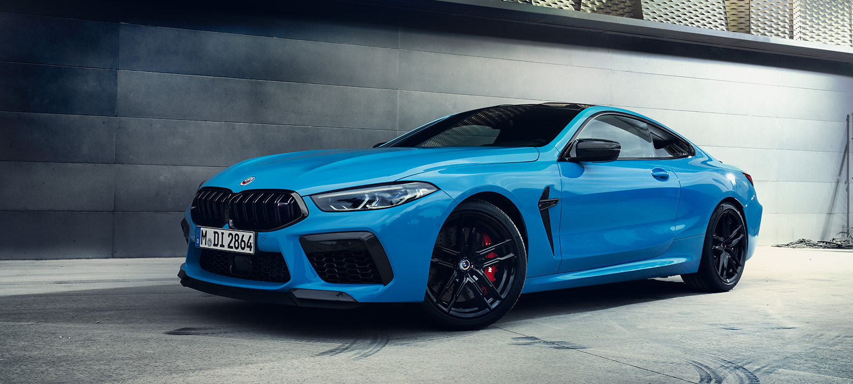 BMW M8 Competition Coupé F92 LCI Facelift 2022 Daytona Beach Blue uni set fra siden let drejet stående foran en mur