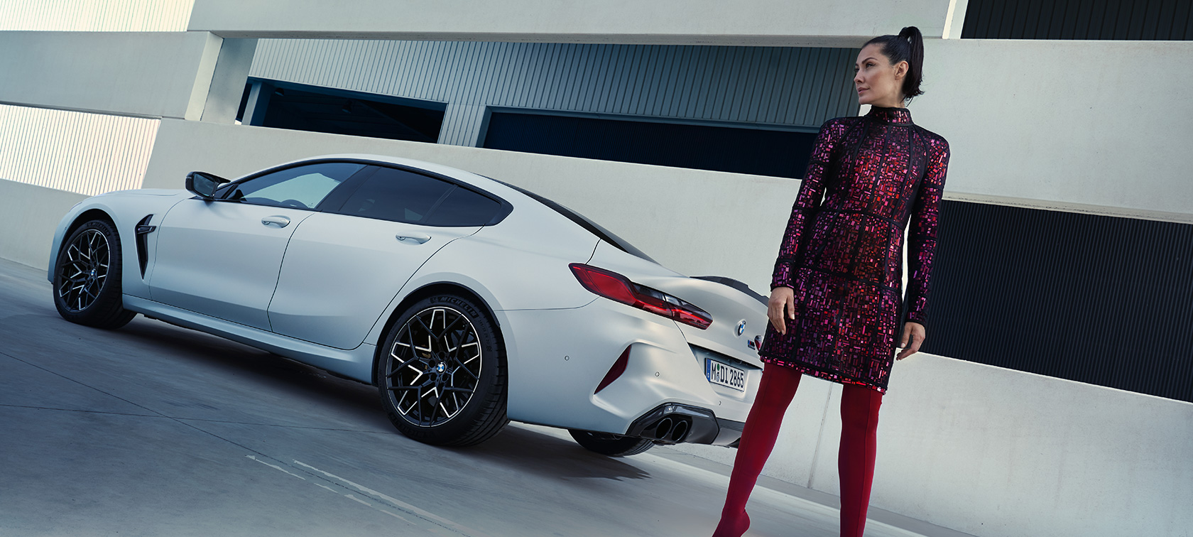 BMW M8 Competition Gran Coupé F93 LCI 2022 set bagfra let drejet BMW M8 Competition Gran Coupé F93 LCI Facelift 2022 BMW Individual Frozen Brilliant White metallic set bagfra let drejet med kvindelig model ved siden af bilen